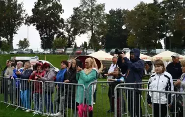 widzimy grupę os&oacute;b stojących za barierkami