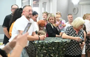 widzimy grupę os&oacute;b stojących obok stolik&oacute;w