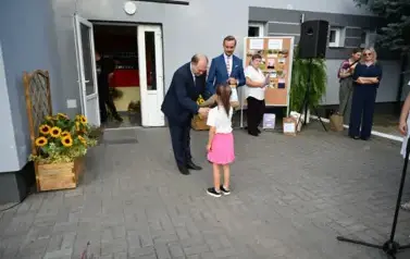 widzimy pana przekazującego upominek dziewczynce 
