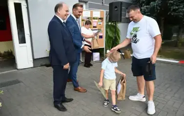 widzimy 3 pan&oacute;w oraz chłopca idącego z upominkiem
