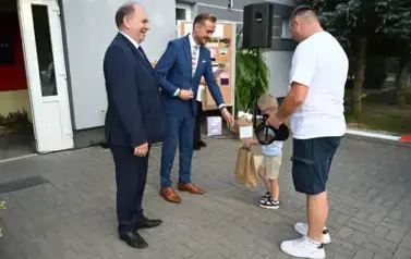 widzimy 3 pan&oacute;w oraz chłopca trzymającego upominek