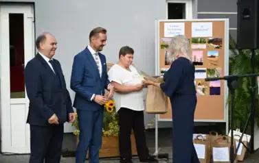 widzimy panią kt&oacute;ra przekazuje upominek drugiej pani