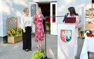 widzimy panią m&oacute;wiącą do mikrofonu oraz 2 panie oraz pana stojących za nią