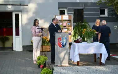 widzimy pana m&oacute;wiącego do mikrofonu oraz dwie panie i pana stojącego za nim