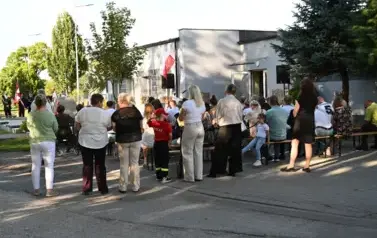 widzimy liczną grupę os&oacute;b stojąca bądź siedzącą na ławkach 