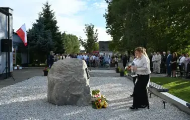 widzimy idącą delegacje pod pomnik z kwiatami oraz zniczem