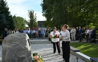 widzimy idącą delegacje pod pomnik z kwiatami oraz zniczem