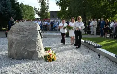 widzimy idącą delegacje pod pomnik z kwiatami oraz zniczem