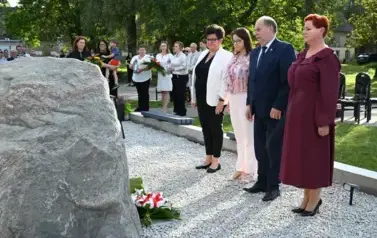 widzimy trzy panie oraz pana stojących na baczność przed pomnikiem