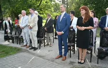 widzimy liczną stojącą grupę os&oacute;b