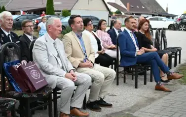 widzimy siedzące na krzesłach osoby oraz na jednym z krzeseł leżą dwie torby prezentowe