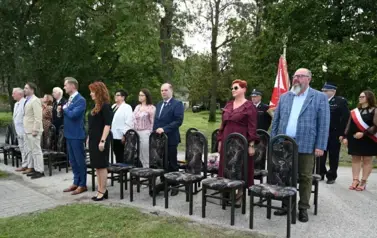 widzimy stojące na baczność osoby, a za nimi stoi delegacja ze sztandarem