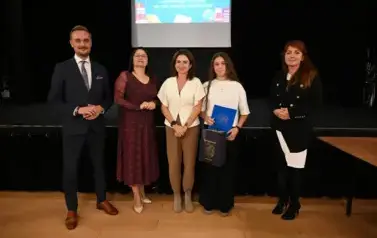 widzimy 3 panie, pana oraz dziewczynkę, kt&oacute;ra otrzymała stypendium i upominek