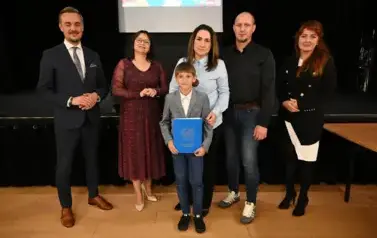widzimy 3 panie, 2 pan&oacute;w oraz chłopca, kt&oacute;ry otrzymał stypendium oraz podarunek