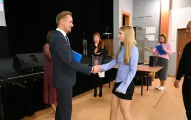 widzimy pana Burmistrza podającego dziewczynce dłoń by jej pogratulować oraz wręczyć jej stypendium