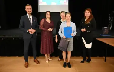 widzimy 3 panie, pana oraz dziewczynkę, kt&oacute;ra otrzymała stypendium i upominek
