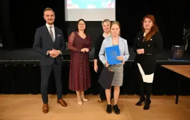 widzimy 3 panie, pana oraz dziewczynkę, kt&oacute;ra otrzymała stypendium i upominek