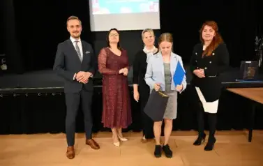 widzimy 3 panie, pana oraz dziewczynkę, kt&oacute;ra otrzymała stypendium i upominek