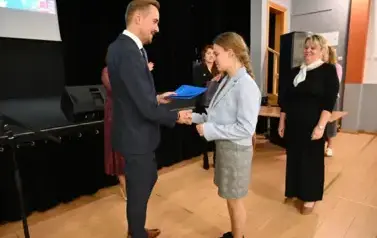 widzimy pana Burmistrza podającego dziewczynce dłoń by jej pogratulować oraz wręczyć jej stypendium