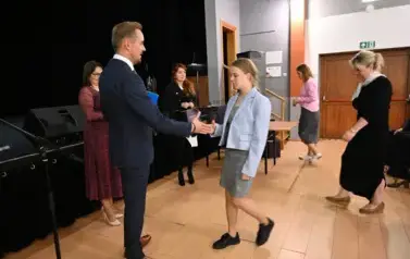 widzimy pana Burmistrza podającego dziewczynce dłoń by jej pogratulować oraz wręczyć jej stypendium