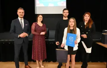 widzimy 2 panie, 2 pan&oacute;w oraz dziewczynke, kt&oacute;ra otrzymała stypendium oraz upominek