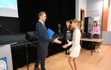 widzimy pana Burmistrza podającego dziewczynce dłoń by jej pogratulować oraz wręczyć jej stypendium
