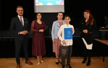 widzimy 3 panie, pana oraz chłopca, kt&oacute;ry otrzymał stypendium i podarunek