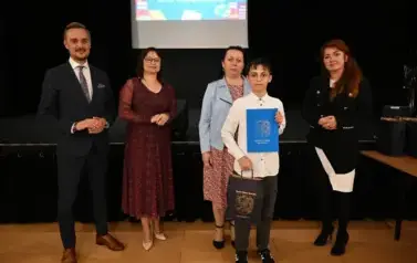 widzimy 3 panie, pana oraz chłopca, kt&oacute;ry otrzymał stypendium i podarunek