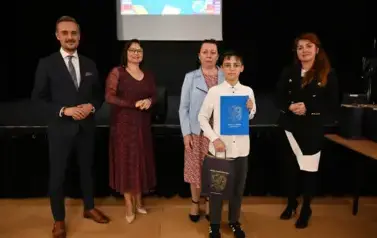 widzimy 3 panie, pana oraz chłopca, kt&oacute;ry otrzymał stypendium i podarunek