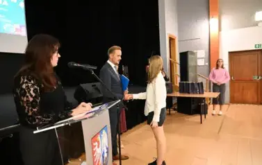widzimy pana Burmistrza podającego dziewczynce dłoń by jej pogratulować oraz wręczyć jej stypendium