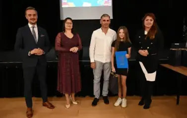 widzimy 2 panie, 2 pan&oacute;w oraz dziewczynke, kt&oacute;ra otrzymała stypendium oraz upominek