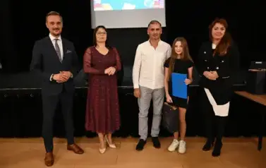 widzimy 2 panie, 2 pan&oacute;w oraz dziewczynke, kt&oacute;ra otrzymała stypendium oraz upominek