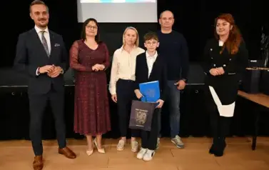 widzimy 3 panie, 2 pan&oacute;w oraz chłopca, kt&oacute;ry otrzymał stypendium oraz podarunek