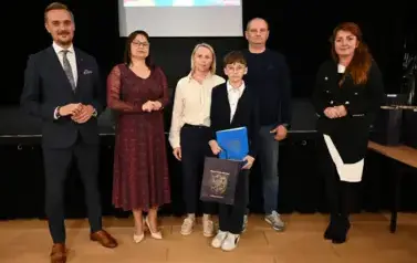 widzimy 3 panie, 2 pan&oacute;w oraz chłopca, kt&oacute;ry otrzymał stypendium oraz podarunek
