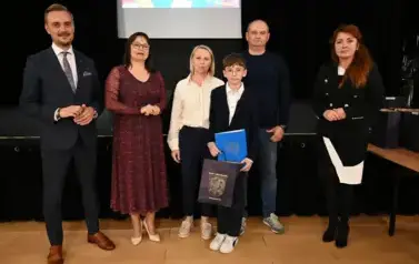 widzimy 3 panie, 2 pan&oacute;w oraz chłopca, kt&oacute;ry otrzymał stypendium oraz podarunek