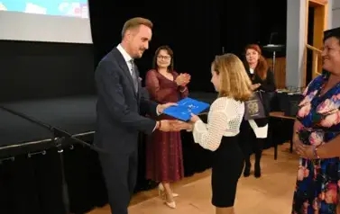 widzimy pana Burmistrza podającego dziewczynce dłoń by jej pogratulować oraz wręczyć jej stypendium