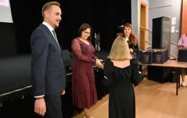 dziewczynka idzie w stronę pani, kt&oacute;ra chce jej pogratulować