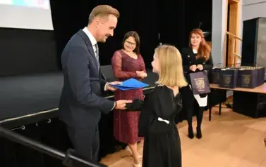 pan Burmistrz podaje ręke dziewczynce by jej pogratulować oraz wręczyć stypendium i upominek