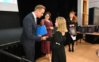 pan Burmistrz podaje ręke dziewczynce by jej pogratulować oraz wręczyć stypendium i upominek