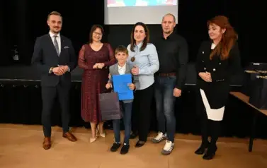 widzimy 3 panie, 2 pan&oacute;w oraz chłopca, kt&oacute;ry otrzymał stypendium oraz podarunek