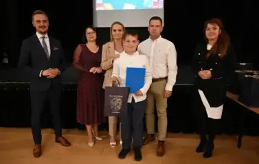 widzimy 3 panie, 2 pan&oacute;w oraz chłopca trzymającego stypendium oraz upominek