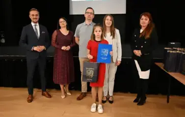 widzimy 3 panie, 2 pan&oacute;w oraz dziewczynkę, kt&oacute;ra otrzymała stypendium