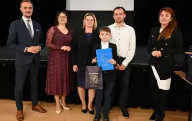 widzimy 3 panie, 2 pan&oacute;w oraz chłopca trzymającego stypendium oraz upominek
