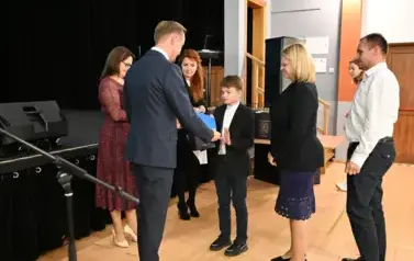 Pan Burmistrz przekazuje chłopcu stypendium oraz podarunek