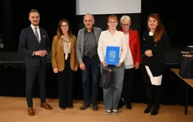 widzimy 3 panie, 2 pan&oacute;w oraz dziewczyne, kt&oacute;ra otrzymała stypendium oraz podarunek