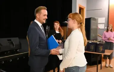 widzimy pana Burmistrza podającego dzieczynke dłoń by jej pogratulować oraz wręczyć jej stypendium