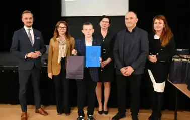 widzimy 3 panie, 2 pan&oacute;w oraz chłopca, kt&oacute;ry otrzymał stypendium oraz podarunek