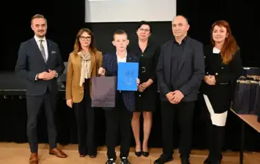 widzimy 3 panie, 2 pan&oacute;w oraz chłopca, kt&oacute;ry otrzymał stypendium oraz podarunek