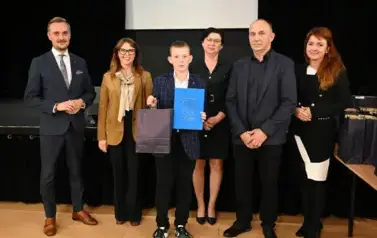 widzimy 3 panie, 2 pan&oacute;w oraz chłopca, kt&oacute;ry otrzymał stypendium oraz podarunek