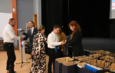 widzimy 3 panie, 2 pan&oacute;w oraz chłopca, kt&oacute;ry otrzymał stypendium oraz podarunek
